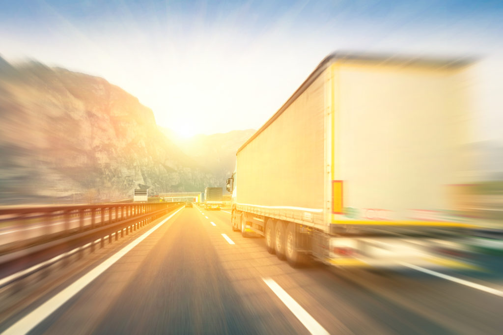 Top Tips To Avoid A Truck Accident - Generic semi trucks speeding on the highway at sunset - Transport